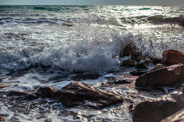 surging waves on a rocky seashore on a sunny day