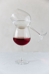 two wine glasses on a grey background one with red wine and the other with water