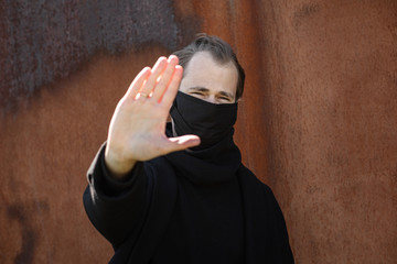 Handsome man wearing a mask on the streets of the city. Closeup of a young man in a respirator to protect against infection with influenza virus or coronavirus