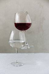 two wine glasses on a grey background one with red wine and the other with water