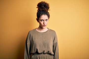 Young beautiful brunette woman with curly hair and piercing wearing casual dress skeptic and nervous, frowning upset because of problem. Negative person.