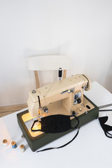 Vintage sewing machine the process of sewing a protective medical mask at home workplace with a house plant ficus