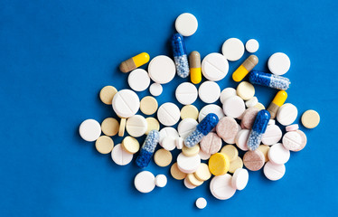 Fototapeta na wymiar Heap of pills, tablets, capsules on blue background. Drug prescription for treatment medication health care concept wth copy space.