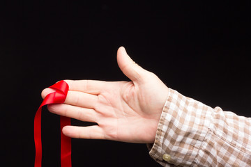 Red ribbon on the hand of an adult person