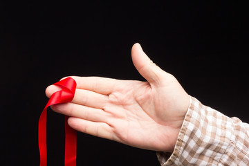 Red ribbon on the hand of an adult person
