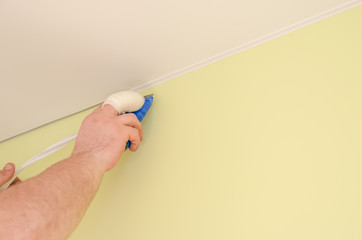 Installation of a decorative skirting Board for a stretch ceiling using a spatula-installation of stretch ceilings