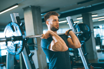 Young man working out with barbells in the gym