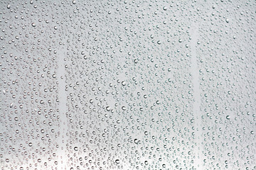 Water drops on a window glass with a cloud sky in the background