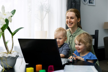 mother with kids using laptop computer and having fun together at home