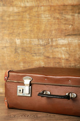 Old shabby leather portable suitcase for travel trip on brown background with copy space