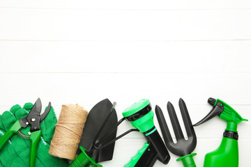 Gardening tools on white wooden background, top view