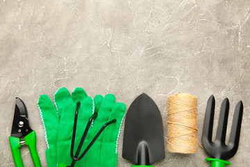 Gardening tools on grey concrete background, top view