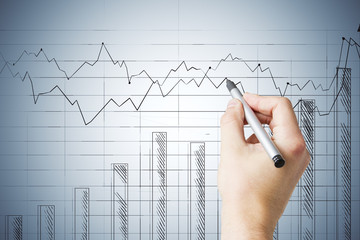 Businessman hand with pen drawing glowing stock chart on screen.
