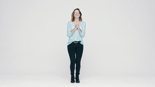 Full length of a young woman feeling excited. Excited woman in eyeglasses standing over white background.

