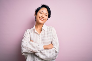Young beautiful asian girl wearing casual shirt standing over isolated pink background happy face smiling with crossed arms looking at the camera. Positive person.