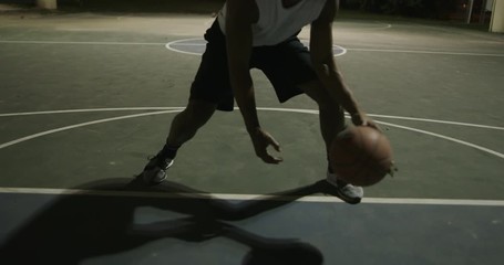Man playing basketball at night - Powered by Adobe
