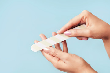 Close up photo of woman doing manicure with nail file.