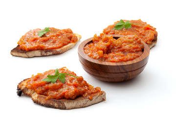 Traditional food from Romania concept with vegetable spread (Romanian: zacusca) on one slices of toast bread and wood bowl isolated on white background