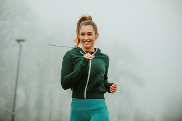 Close photo of pretty sporty woman jogging outdoor on foggy morning.