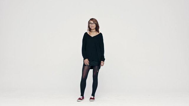Full length of a woman in eyeglasses on white background. Fashionable woman with pierced lips looking at camera.
