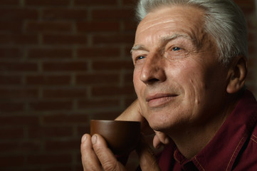 Portrait of smiling senior man drinking coffee at home