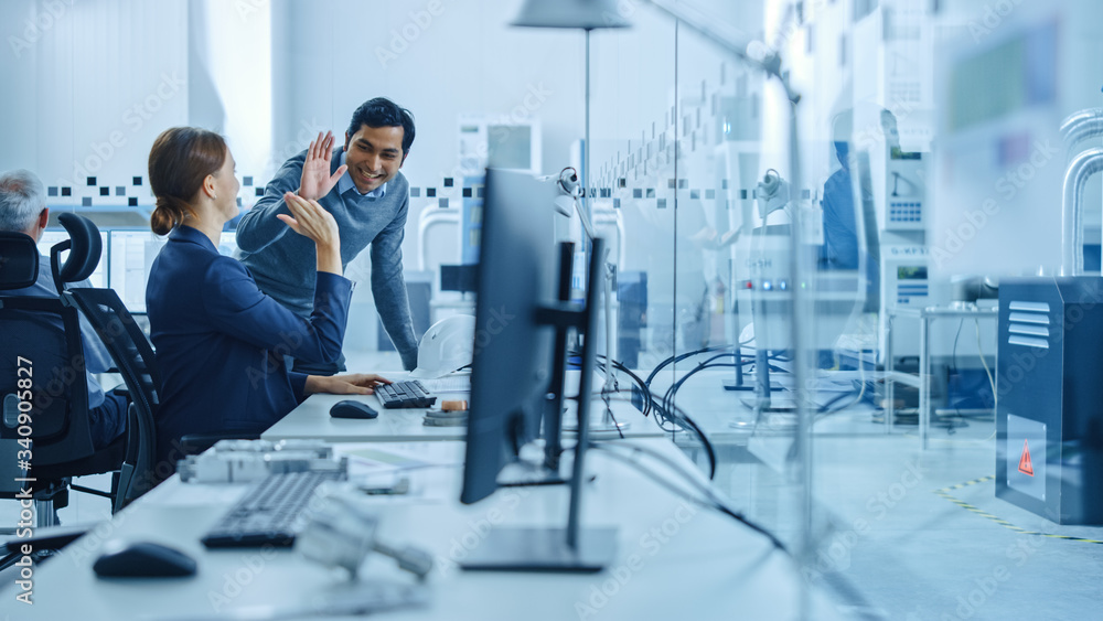 Poster inside factory office: male project supervisor talks to a female industrial engineer who works on co