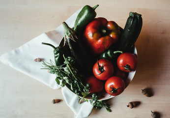 Top view of a bowl with tomatoes, cucumbers, aubergines, red and green peppers and parsley. Bioproducts for a vegetarian diet.