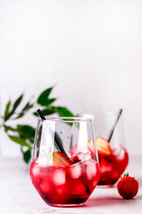 Glasses of Tasty Cranberry Cocktail with Ice Cubes on light Gray Background Alcoholic Drink Straws Vertical