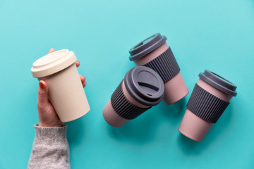 Assorted bamboo travel reusable coffee or tea cups or mags with silicone insulation.Hands open...