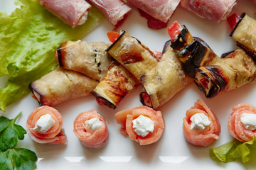 Canapes for receptions, buffets, appetizers for the festive table. Mini rolls of salmon, eggplant, ham with different fillings close-up
