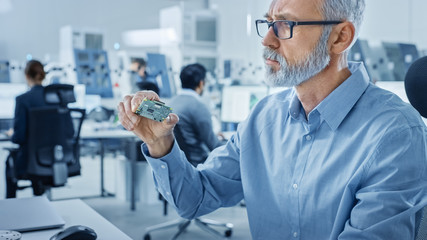 Electronics Design Factory Office: Electrical Engineer Working on Computers, using CAD Software to...