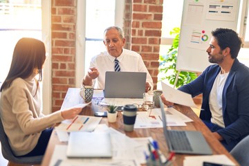 Group of business workers working together. Sitting on desk using laptop reading documents at the office