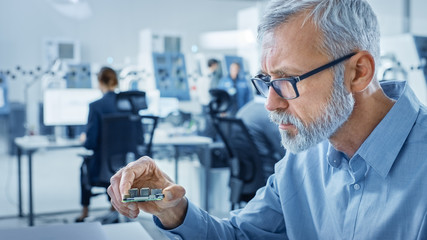 Electronics Design Factory Office: Electrical Engineer Working on Computers, using CAD Software to...