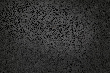 coarse-textured black background with many holes in basalt material. - obrazy, fototapety, plakaty