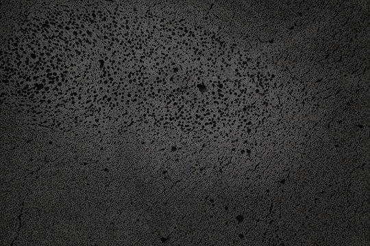 coarse-textured black background with many holes in basalt material.