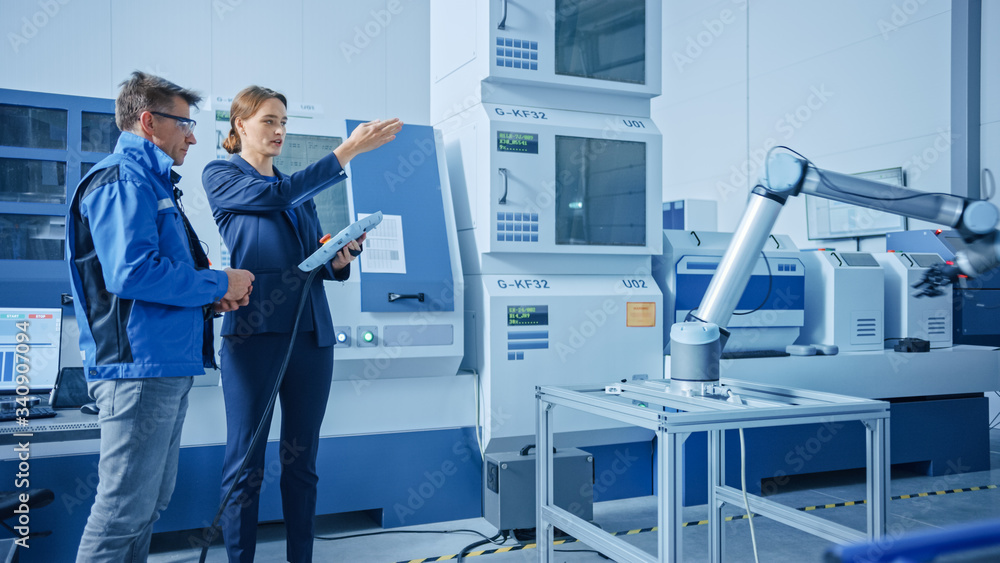 Poster modern factory: female project manager and male engineer standing, talking and using tablet computer