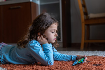 Cute little girl lying down looking at mobile