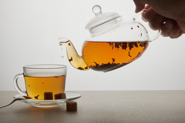 Cup and teapot of green tea with lemon and sugar isolated on white