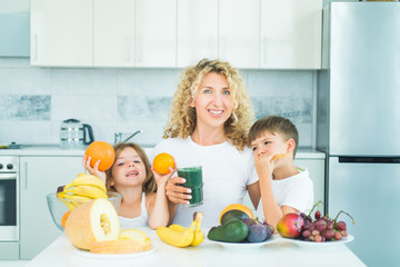 Family mother and chilen daughter and son blended green and orange smoothie with healthy fruits...