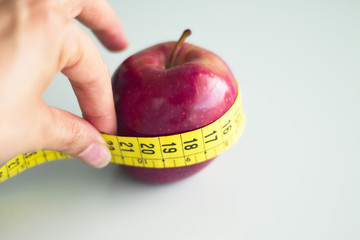 Tape measure surrounding a red apple.
