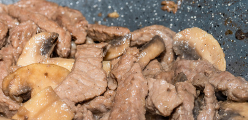 Homemade cooking veal and mushrooms in frying pan. Close-up macro photo of julian chopped meat....