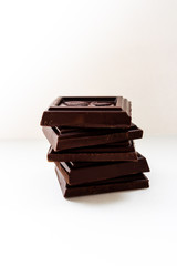 Pieces of delicious milk chocolate on a white plate, side view