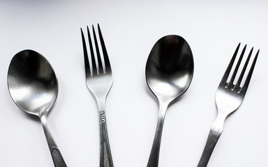 Two spoons and two forks on a white background