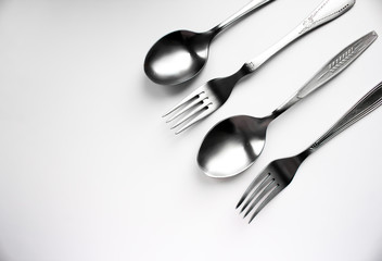 Two spoons and two forks on a white background