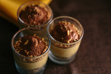 Detail of three dessert glasses with coffee cream and cocoa. On dark background