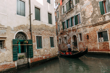 Fototapeta na wymiar A gondolier passing on a gondola through narrow channels past residential buildings | VENICE, ITALY - 16 SEPTEMBER 2018. 