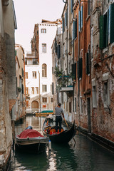 The gondolier standing controls the gondola as it sails through the narrow canal of Venice   VENICE, ITALY - 16 SEPTEMBER 2018.  © Руслан Секачев