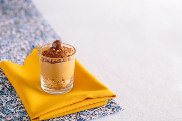 Dalgona coffee presented in a small glass, accompanied by cocoa