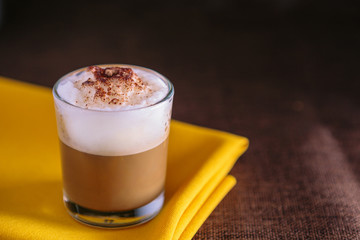 Mini cappuccino presented in a small glass. On black background