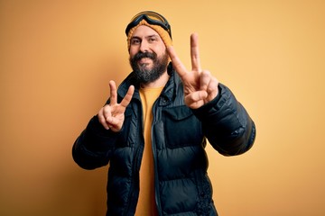 Handsome skier bald man with beard skiing wearing snow sportswear and ski goggles smiling looking...